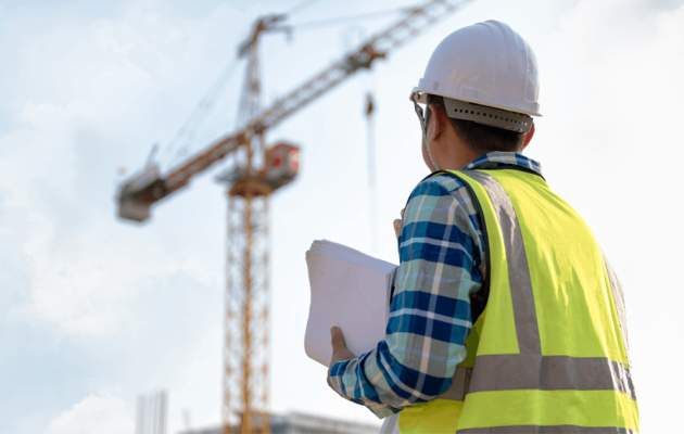 Construction Worker Looking at Building Crane